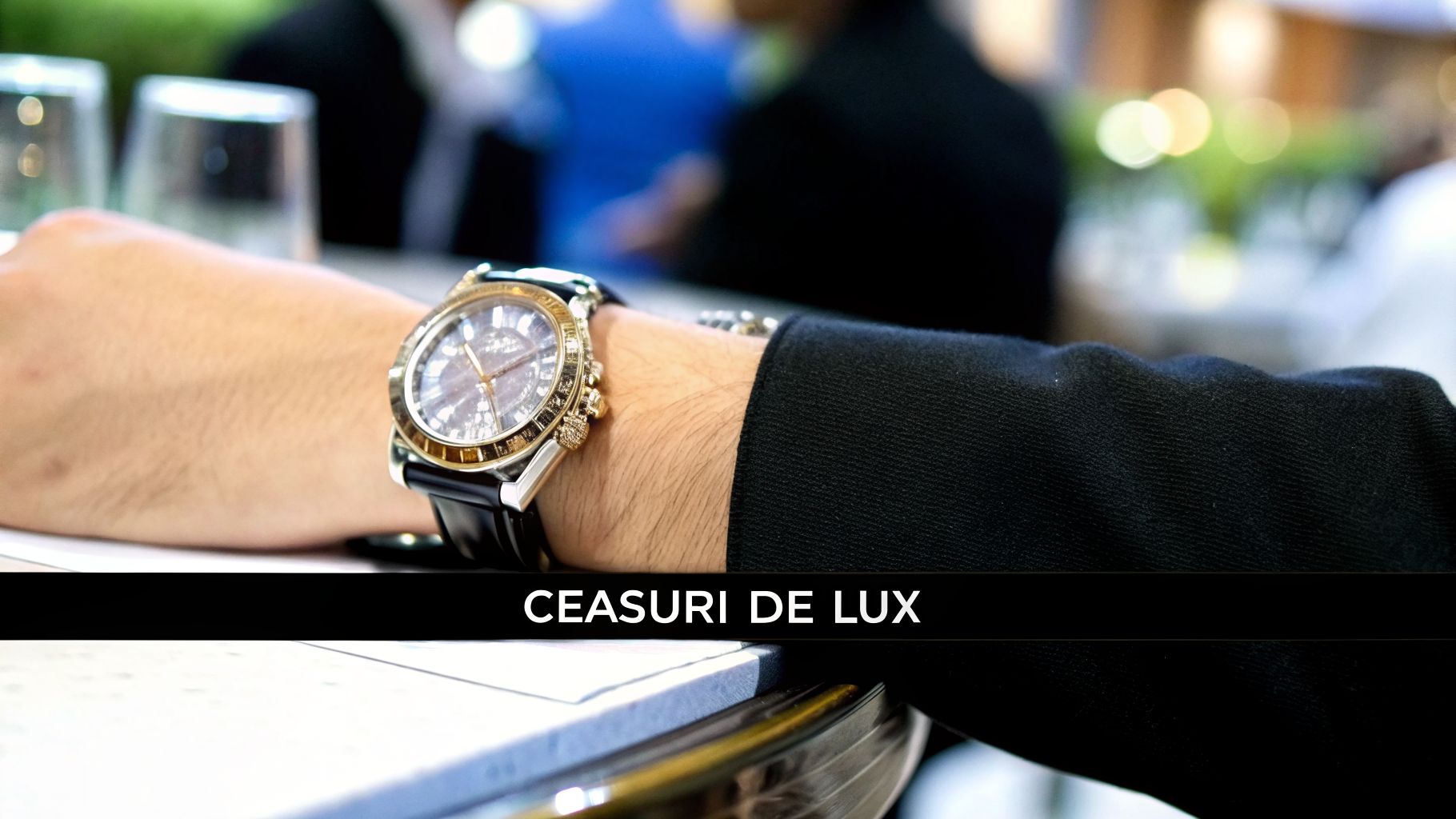 Brațul unei persoane purtând un ceas de lux elegant, cu o curea neagră, într-un cadru sofisticat.
